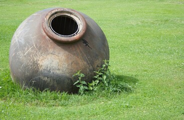 Großes Tongefäß auf einer Wiese als Gartendeko.