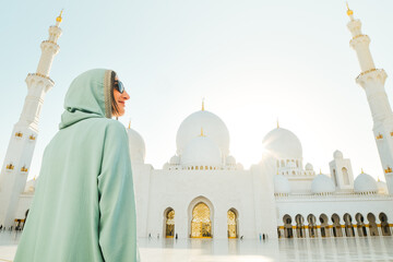 Abu Dhabi, UAE - april 25th, 2025: woman traveler wear stylish abaya sightseeing Sheikh Zayed Grand Mosque in Abu Dhabi on beautiful sunset. Free entrance mosque visit entrance famous destination