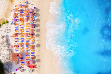 Summer vacation and rest. Beach, people and umbrellas. Top view from drone at the beach and azure sea. View on the coast from drone. Background, wallpaper, postcards.