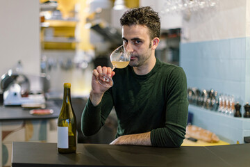Sommelier tasting white wine in restaurant: professional wine expert evaluating beverage quality