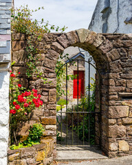 Stone archway with gate and red roses.