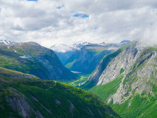 Norwegian fjord. High mountains and forest. Clouds over the rocks. Vacation and travel in summer Norway. Wallpaper, postcard, background. Place for mountain hiking, travel and vacation.