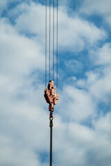 Fototapeta premium Industrial Crane Hook and Pulley Block System Against Cloudy Blue Sky from Below