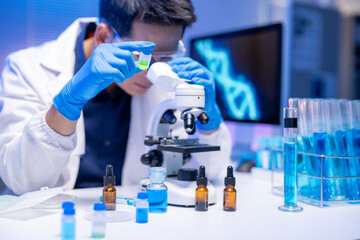 A man is looking at a green liquid under a microscope