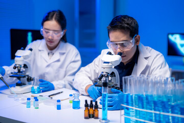 Two scientists are looking through microscopes