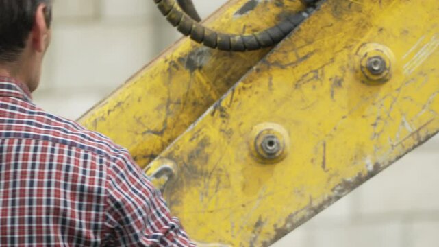 Construction Machine Arm Worker in plaid shirt with yellow equipment detail