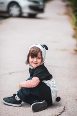A mischievous little kid sitting on the pavement