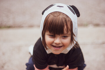 A mischievous little kid sitting on the pavement