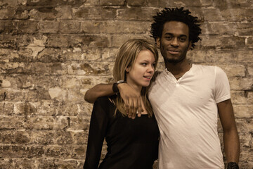 Urban Couple. Candid image of an attracitve young mixed race couple set against a brick wall with...
