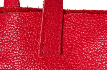 A fragment of the handle of a red leather bag, showing the grainy texture of the material and the...