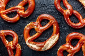 Pretzel or Bretzel, traditional German beer snack, a wheat bread with salt, overhead flat lay shot on a black background, a pattern