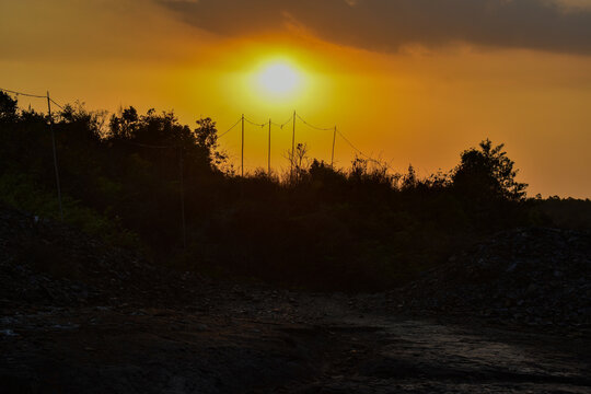 Radiant sunset over silhouetted trees and rural landscape, capturing the golden hour in Jowai , Meghalaya.