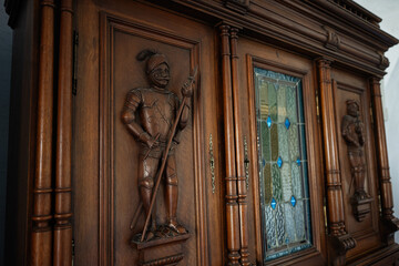Antique wooden cabinet with carved knight details and stained glass accents