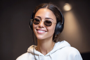 Smiling woman wearing headphones and sunglasses listening to music.