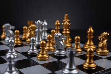 Golden and silver chess include king queen horse ship and pawn on dark background