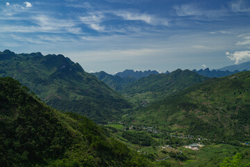 The road winds through the mountain, revealing a scenic landscape where nature meets the sky,...