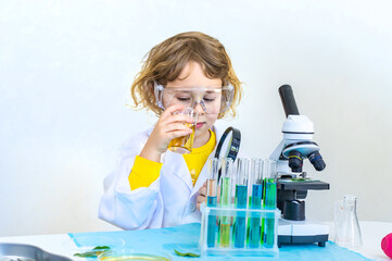 Laboratory examination of a child with test tubes, reagents and a microscope. Selective focus.