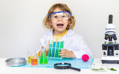 Laboratory examination of a child with test tubes, reagents and a microscope. Selective focus.