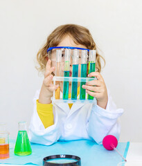 Laboratory examination of a child with test tubes, reagents and a microscope. Selective focus.