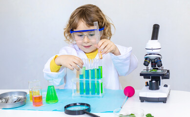 Laboratory examination of a child with test tubes, reagents and a microscope. Selective focus.