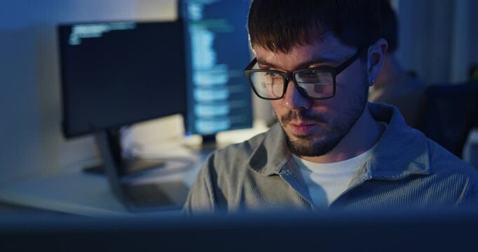 Team adult male freelance developer work late typing write prompt AI bot app program nomad terminal code at office night. Artificial intelligence dashboard, robotics, user interface, machine learning.