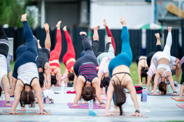 A group of people are doing yoga on the ground. There are many people in the group, and they are all doing different poses
