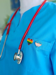 Scrubs in vibrant blue feature heart-shaped pins showcasing rainbow and transgender pride flags concept