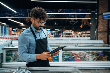 Manager is with notepad. Male worker is in the grocery store