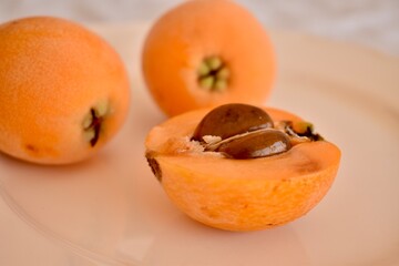Golden loquat resting on a rustic tabletop. Simple and clean composition with natural lighting and...