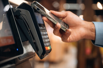 Wireless transfer. Close up view of man customer that is paying for products by credit card in grocery store