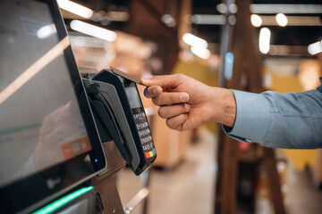 Wireless transfer. Close up view of man customer that is paying for products by credit card in...