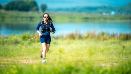 Obraz premium A woman is running in a field with a tennis racket in her hand. She is wearing a blue shirt and shorts