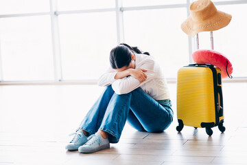 Sad woman sitting at the airport with luggage, feeling emotional and reflecting while waiting for...