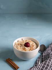 Porridge bowl with fresh fruit and cinnamon on light blue background. Healthy, vegetarian breakfast ready to take care of yourself in the morning