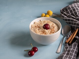 Porridge bowl with fresh fruit and cinnamon on light blue background. Healthy, vegetarian breakfast ready to take care of yourself in the morning