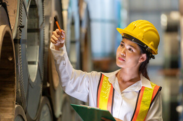 Asian woman engineer in uniform inspection warehouse and check control heavy machine construction...