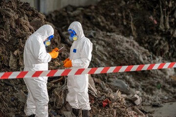 Two scientists or researchers in full protective suits with face masks gloves and goggles...