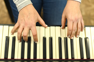 Hands of a musician playing contemporary electronic piano, highlighting rhythm and harmony