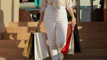 Stylish female navigating staircase, holding colorful shopping bags, expressing confident retail enthusiasm with bright smile and energetic movement.Consumerism, sale, purchase, shopping, shopping,