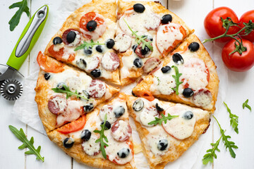 Italian pizza with salami mozzarella, tomatoes, olives and arugula. Delicious pizza for lunch. View from above. Close-up