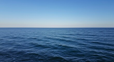 Obraz premium Serene ocean view on a clear, sunny day. Gentle waves meet a tranquil horizon under a vast blue sky