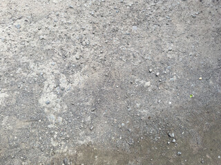 Dry gravelly ground surface with scattered stones and light gray natural texture
