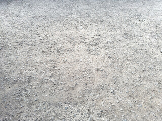 Light-colored rough ground surface with scattered gravel and dry earthy texture