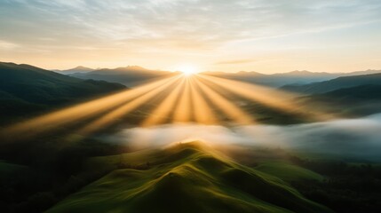 Experience the breathtaking beauty of a sunrise illuminating rolling hills and mountains, with rays of sunlight breaking through mist for a captivating view.
