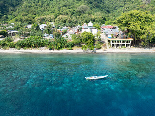 A small boat rests near a coral reef fringing the island of Alor, Indonesia. This tropical area is fast becoming popular for divers and snorkelers due to its biodiverse coral reefs.