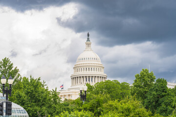 U.S. Capitol stands tall amid dark clouds and summer foliage in the nation's capital.