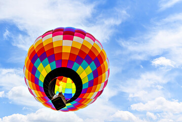 Colorful hot air balloon flying over blue sky with white clouds	