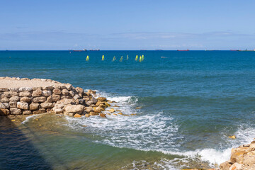 Blue Mediterranean Sea with distant ships and a rocky breakwater in Haifa.