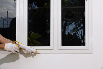 Handyman using acrylic sealant caulk the outside window frame..