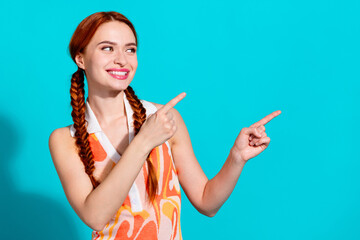 Photo of pretty young woman look point fingers empty space wear dress isolated on teal color...